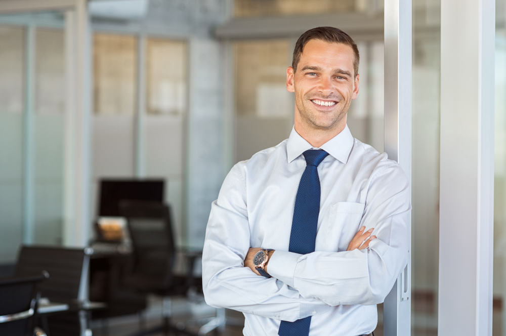 businessman stands in front of blurred office background