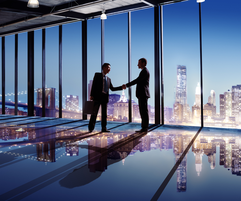 businessmen shake hands in front of windows