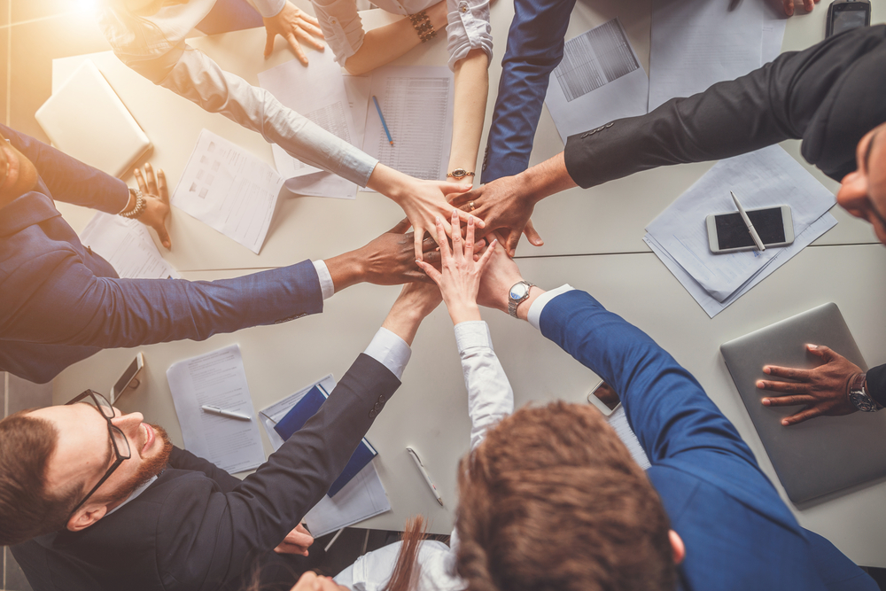 group forms a hand stack over a desk