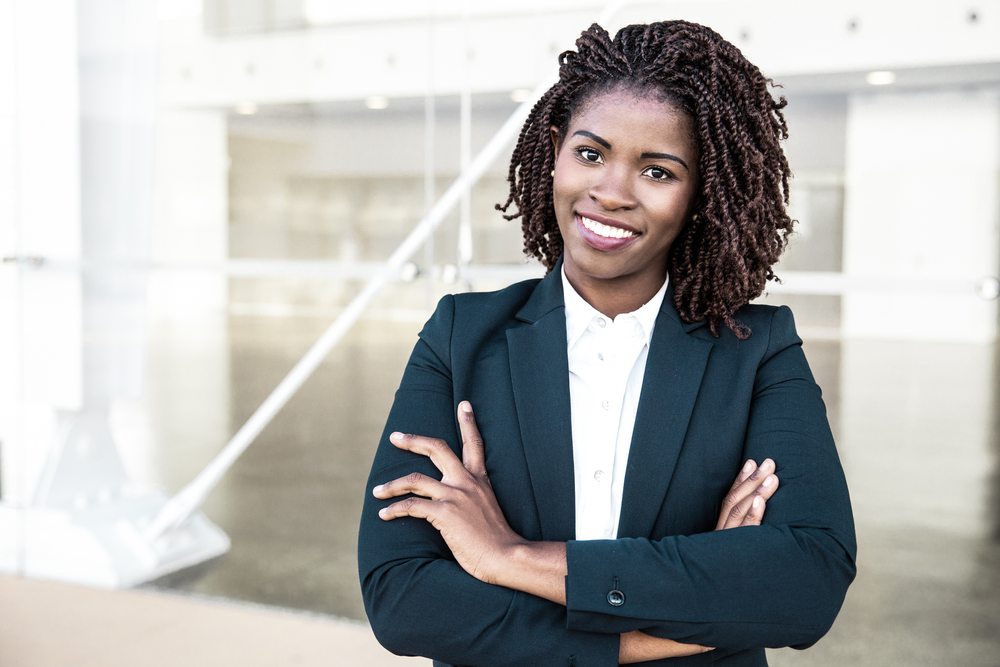 smiling businesswoman stands with arms crossed
